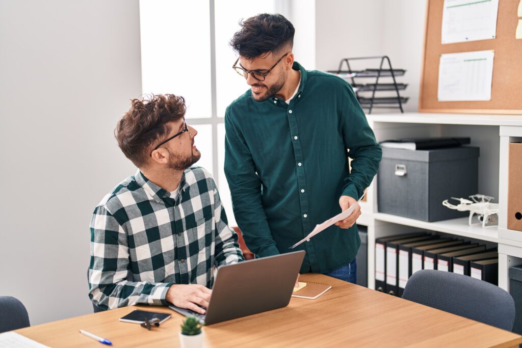 Young couple business workers using laptop reading document working at office