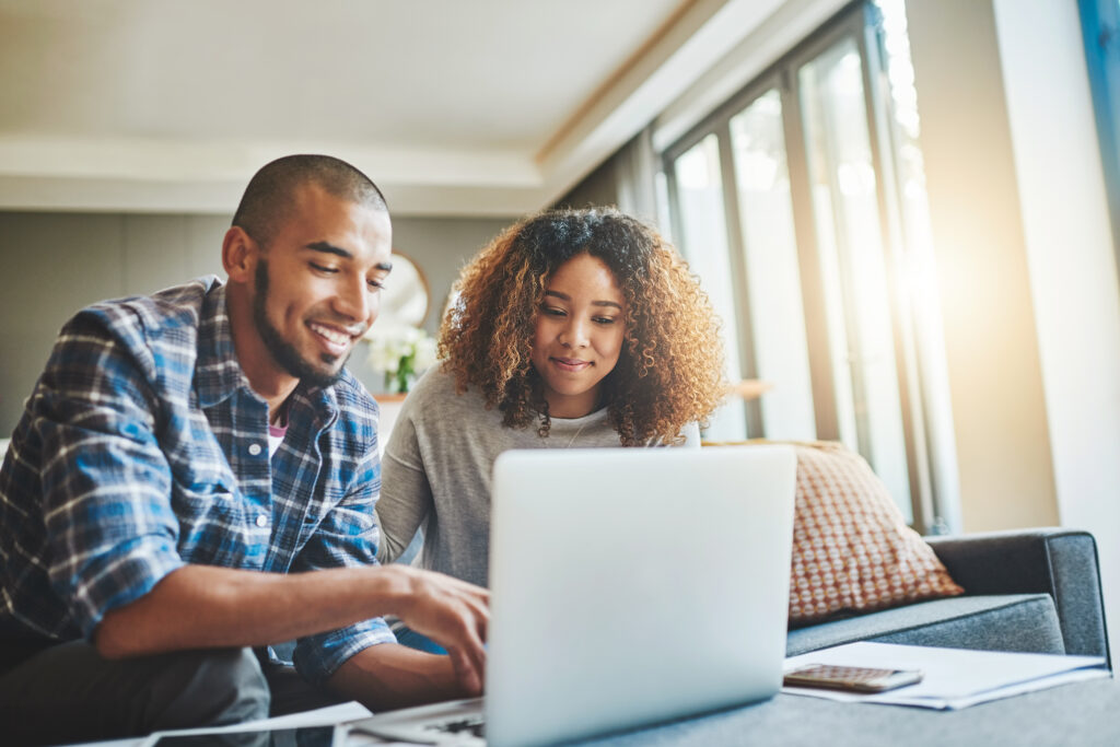 Managing money matters with wireless technology. Shot of a young couple using a laptop while working on their home finances.